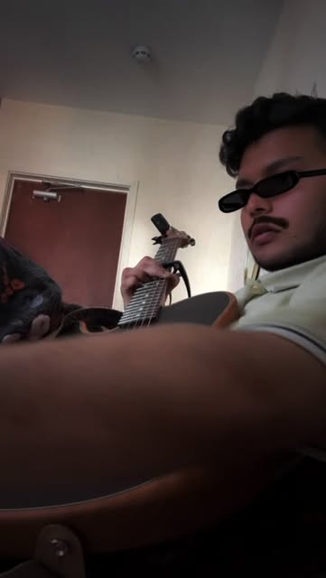 Krish playing an acoustic guitar in sunglasses
